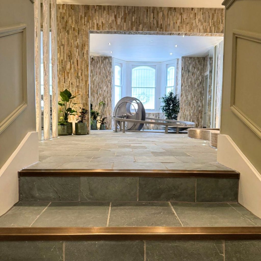 Slate steps and walls leading into Splitface stone walls in a water play area in a nursery London. 